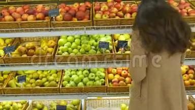 女人在杂货店挑选新鲜的红<strong>苹果</strong>，然后把它放进塑料袋里。 年轻漂亮的女孩