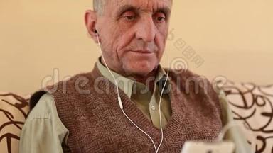 戴着白色智能手机的老人坐在沙发上听音乐