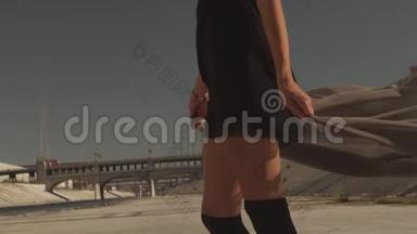 美丽的女孩与挥舞的织物定位，跳舞，跑步，走在洛杉矶河。工业区时尚视频拍摄。