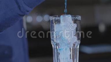 蓝色饮料倒入玻璃杯中。 加冰和鸡尾酒的杯子。 <strong>酒吧</strong>里的异国情调饮料。 慢动作。