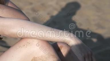穿着黑色泳衣的海滩上的女孩涂了<strong>防晒霜</strong>或<strong>防晒霜</strong>。 在海边的沙滩上