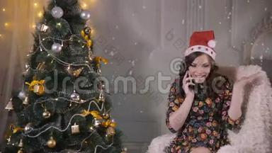 年轻可爱的英俊女孩在圣诞树附近用<strong>手机</strong>说话。 圣诞<strong>节</strong>庆典。