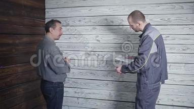 工人和要求苛刻的顾客在木墙的背景上讨论和发誓。 施工中的问题。