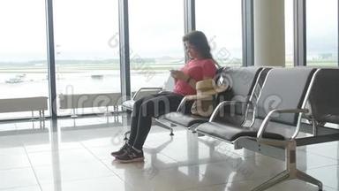 一位年轻的女士<strong>在机场</strong>等待出发，看着智能手机