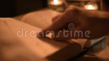 大特写女魔术师在一个黑暗的房间里，烛光在寻找一本书中的咒语。 低键带电摄像机.. 神秘
