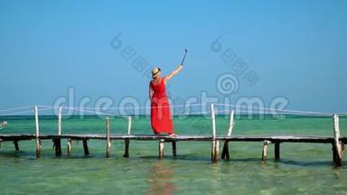 一位漂亮的女士用自拍棒上的动作相机拍摄自己的视频。 岛上阳光明媚。 普惠