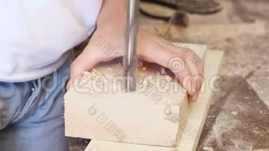 工人在木模板上钻洞。 木制玩具的制造。 特写双手。