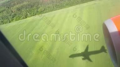晴天的地面上飞行飞机的影子.. 从飞机窗口观看。 飞机的影子。 在空中飞行