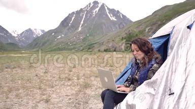 女游客带着笔记本电脑，指纹，作品。 坐在扶手椅上的群山之中
