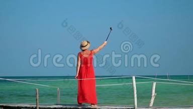 这位年轻的美女在绿松石透明水中间的一个码头上花钱。 一位漂亮女士拍了一段视频