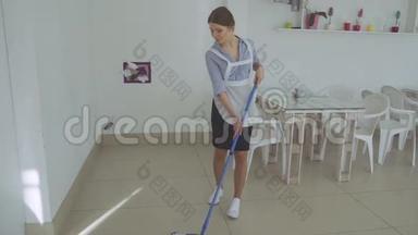做梦的女仆在洗地板。 女孩在餐馆里打扫地板拖把