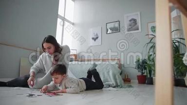 妈妈带着一个孩子在他家白色的内部和他的小儿子<strong>一起</strong>收集<strong>拼</strong>图。 快乐