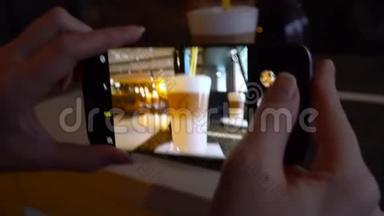 女孩在一家咖啡馆里用智能手机拍拿铁的照片