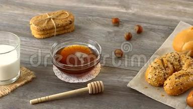 蜂蜜，牛奶，饼干和新鲜的小面包放在乡村的木桌上。 乡村早餐。