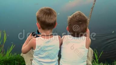 两兄弟在露天捕鱼。 两个小孩子在达查的一个池塘里钓鱼。 夏天美丽的湖