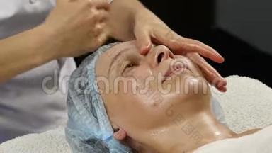 在SpaSaton进行塑料面部按摩。 妇女享受专业按摩治疗师的服务。 4K