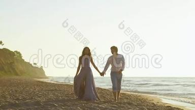 迷人的深爱的年轻一对一起在海滩上散步。 浪漫蜜月概念
