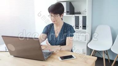一位漂亮的中年女商人，办公室里有一台笔记本电脑