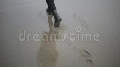 暴风雨时，穿着粉红色外套的快乐女孩在海边。 大海在沙滩上冲刷着脚印