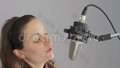 女孩在演播室麦克风里唱歌