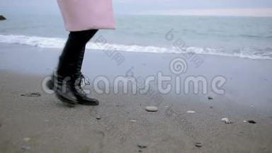 暴风雨时，穿着粉<strong>红色</strong>外套的快乐女孩在<strong>海边</strong>。 大海在沙滩上冲刷着脚印