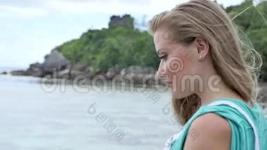 夏天，穿着白色工作服的漂亮年轻女子站在木墩上看着海洋。