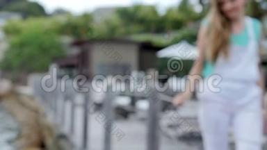 年轻漂亮的女人穿着白色工作服，在豪华度假村附近的<strong>木墩</strong>上散步。