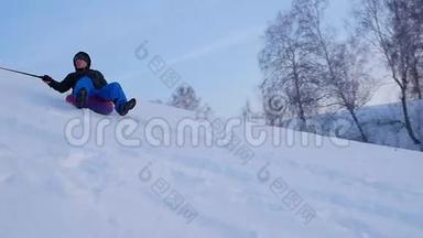 快乐的人骑着雪管在雪道上微笑。慢动作。 冬天的雪景。 户外运动