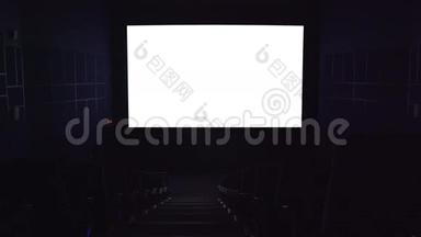 电影院的大厅。 电影院的白色屏幕为您的模板。 电影院里的观众