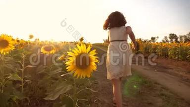 日落时，小女孩带着向日葵跑过田野。 慢动作视频。 日落时跑在田里的女孩