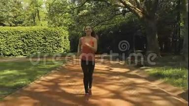 在美丽的夏日阳光下，慢跑的女人在城市公园里奔跑。