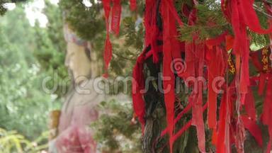 红色丝带包裹在树枝上。 寺庙中的中国Fortuna雕塑。历史雕塑和纪念碑。