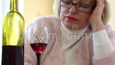 沮丧的老妇人坐着看着一瓶酒