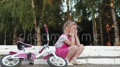 一个穿着粉<strong>红色</strong>裙子的小女孩坐在<strong>台阶</strong>上的公园里，戴着耳机享受着智能手机。