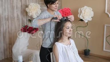 化妆师和模特一起工作。 理发师做模特的发型。 女人和一个设计师一起工作