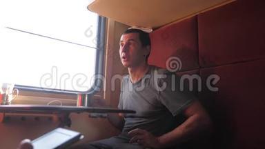 男人坐在<strong>火车车厢</strong>里，捧着咖啡喝茶。 慢动作视频。 男人