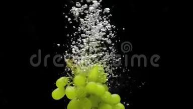 绿色葡萄枝在黑色背景上落入透明水