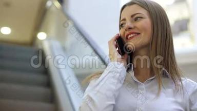 年轻的微笑的女人在商场里用手机说话