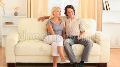 快乐的年轻夫妇在沙发上<strong>为</strong>遥控器<strong>而战</strong>