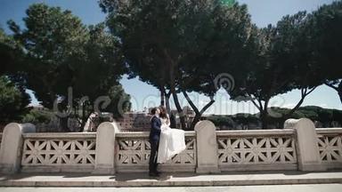 意大利罗马浪漫石桥上的婚礼<strong>情侣</strong>。 时髦的新郎和漂亮的新娘接吻。 意大利的<strong>蜜月</strong>