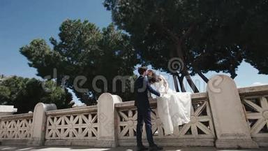 罗马浪漫石桥上的婚礼情侣。 时髦的新郎和漂亮的新娘接吻。 意大利、欧洲的蜜月