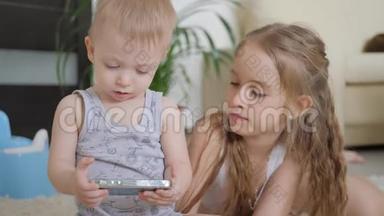 可爱的弟弟妹妹使用数字平板电脑，微笑着，看上去很开心。 兄弟姐妹玩得开心
