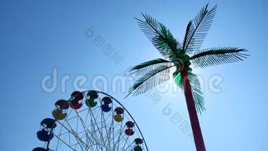 游乐园。 摩天轮越过蓝天。 游乐园和棕榈