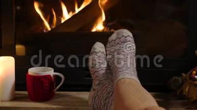女人坐在壁炉旁，端着一杯热饮和一本书