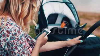 母亲<strong>摇摆</strong>婴儿<strong>车</strong>和使用智能手机在公园。 夏日阳光明媚。
