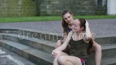 两个可爱的少女<strong>女友</strong>坐在公园的石阶上聊天。