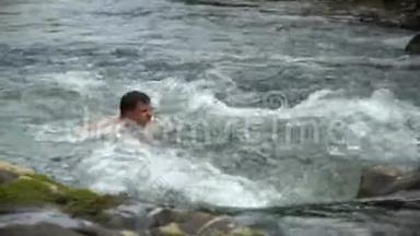那家伙正在河里游泳。 一个年轻可爱的家伙在一条干净的山河里洗澡。 他很开心。
