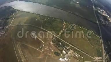 专业跳伞运动员在绿色田野，河流上空飞行。 极端。 身高