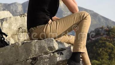 年轻的金发女郎坐在<strong>山崖</strong>边上，与美丽的山峰相映成趣