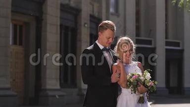新娘和新郎在城市的柱子中行走。 亲吻和拥抱相爱的一对